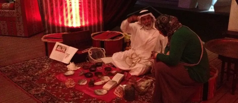Visitors viewing traditional crafts displayed on carpets in a cultural pavilion
