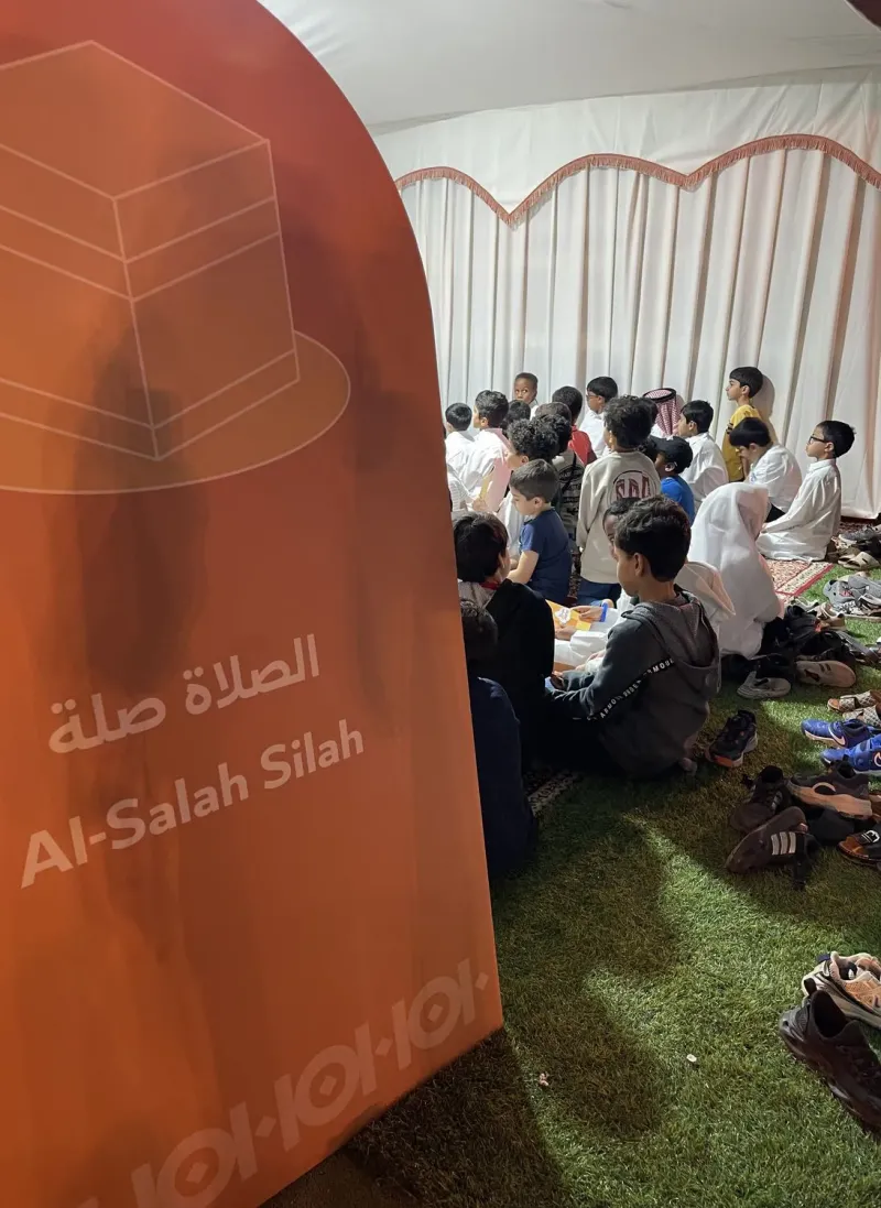 Branded banner beside children seated on grass during the Bunyan event