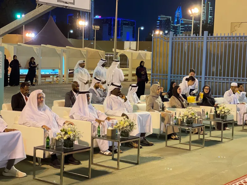 Dignitaries seated on white sofas at an outdoor evening launch event