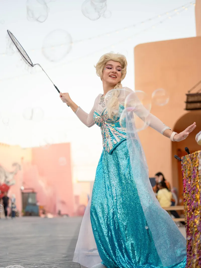 Costumed ice-princess character with a bubble wand at Old Doha Port during Eid