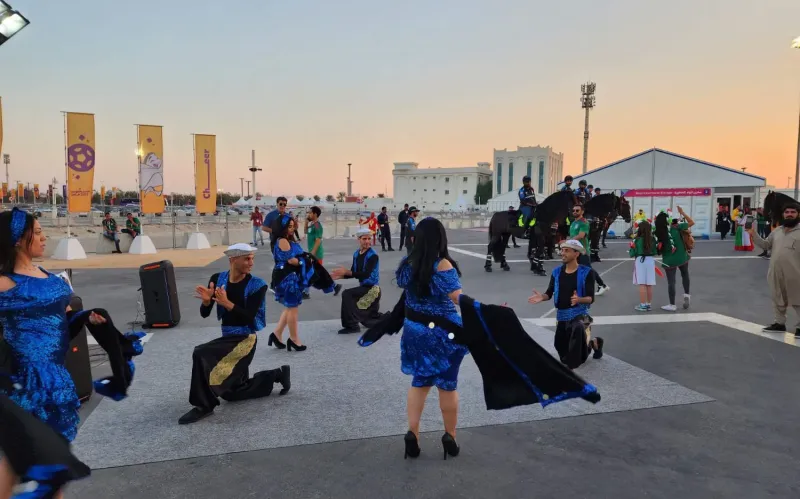 Dancers in blue costumes performing at sunset on a fan festival plaza