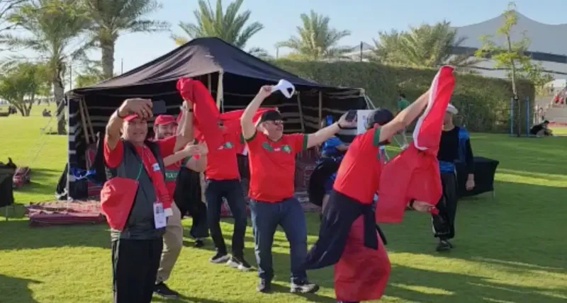 Performers in red outfits dancing outside a tent on a grass lawn
