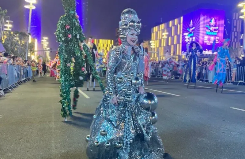 Performer in a silver mirrored costume walking in a night parade