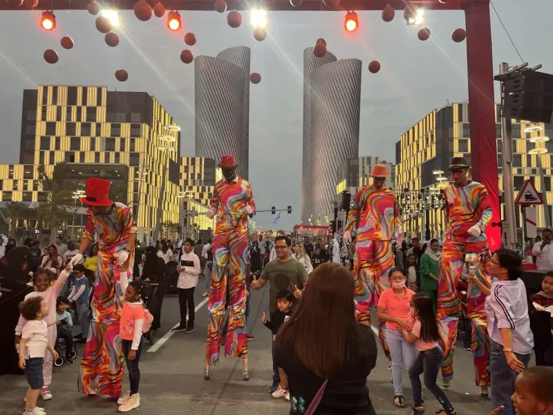 Stilt walkers in colourful costumes among families on Lusail Boulevard