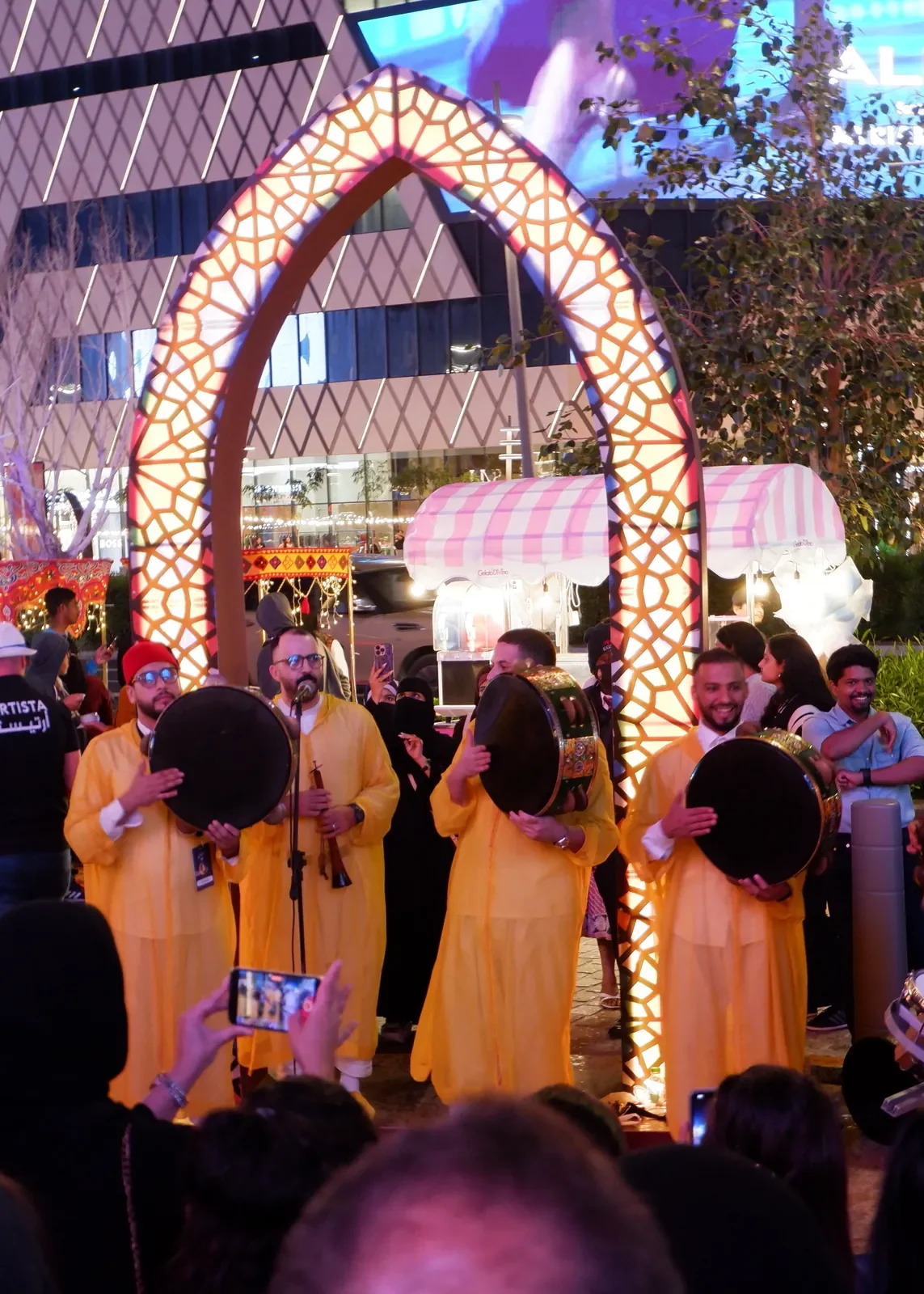 Drummers in yellow robes performing under lit Ramadan arches at Lusail Boulevard