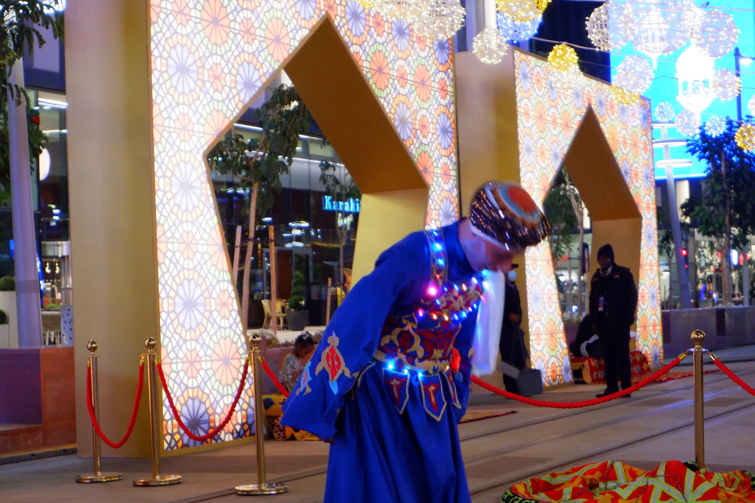 Dancer in a blue costume leaning forward in front of golden star arches