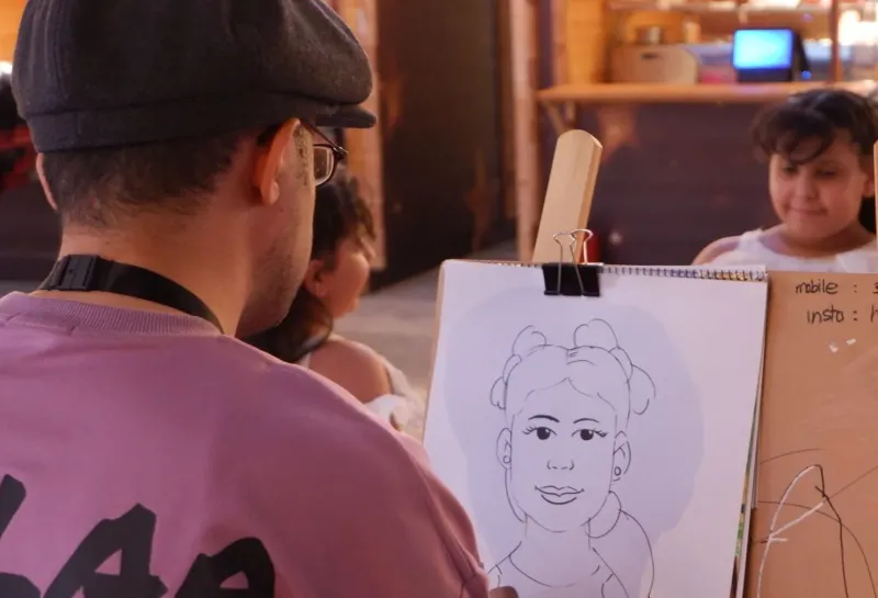 Live caricature artist sketching a child's portrait at an event
