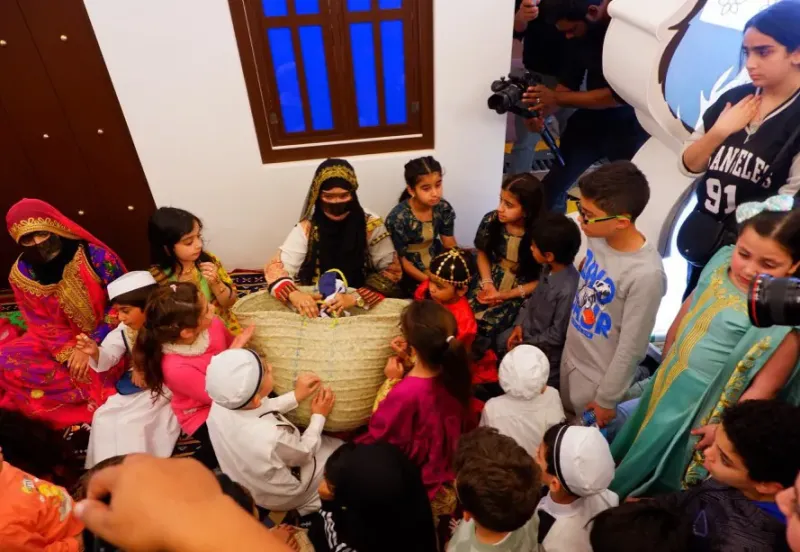 Children seated in a circle around a storyteller in traditional dress during a Ramadan activity