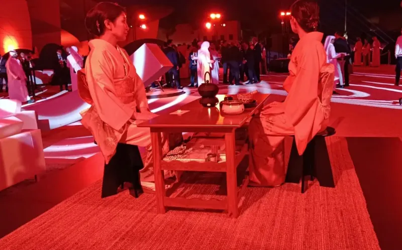 Two guests seated at a low table in a red-lit immersive space