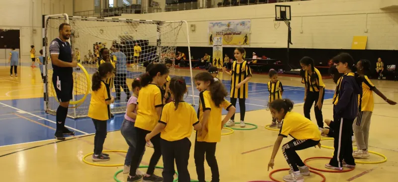 Summer camp children playing floor hoop games in an indoor sports hall