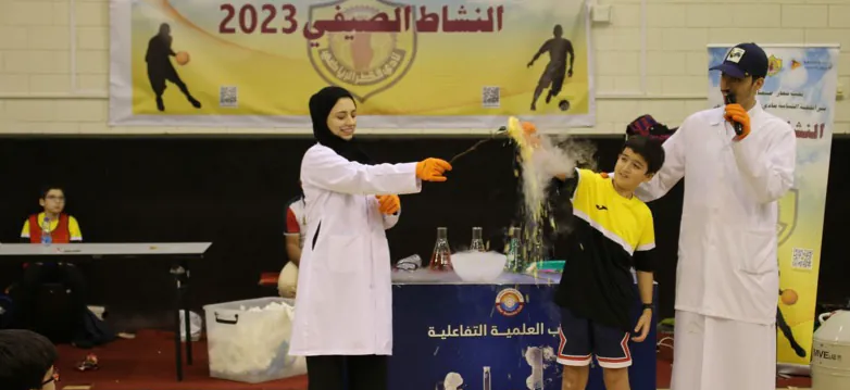 Instructor in a lab coat performing a science demonstration for children at summer camp