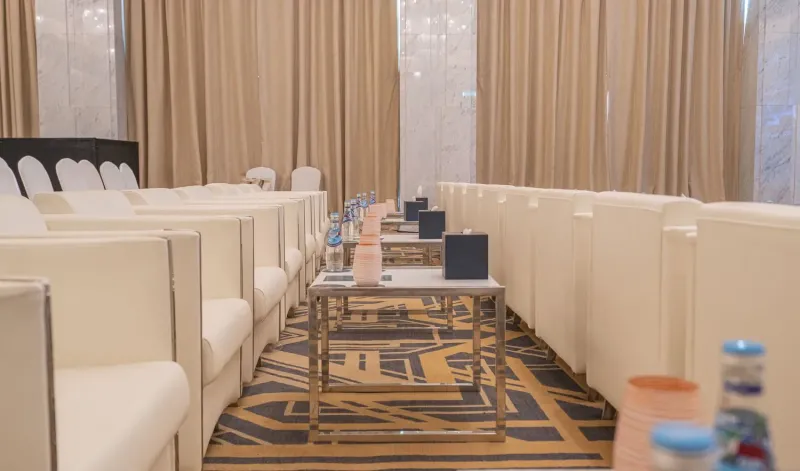 Rows of white armchairs in a hotel ballroom prepared for guests