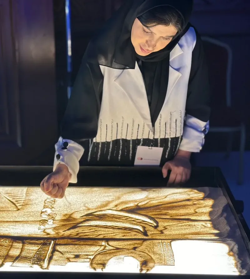 Female sand artist creating a live sand painting at the launch event