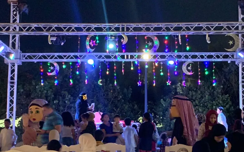 Ramadan crescent decorations over a steel truss stage with guests seated below