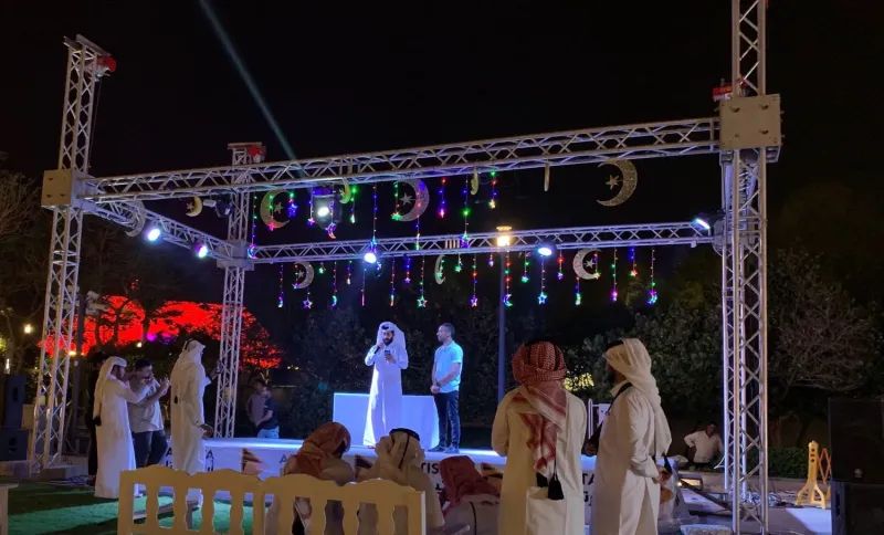 Festival stage framed by crescent-moon lights with a seated audience at night