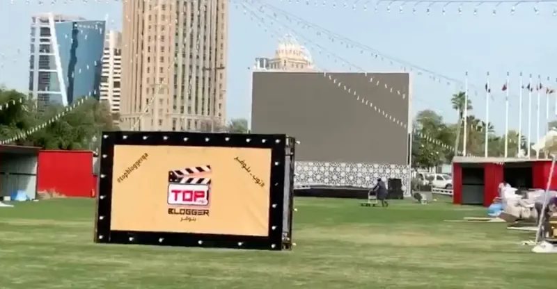 Illuminated festival clapperboard sign in front of a large outdoor screen