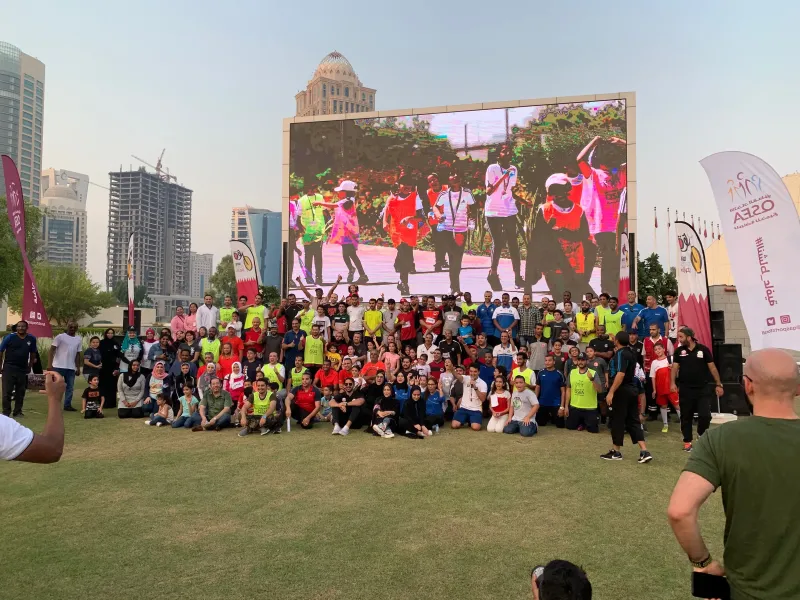 Large group of participants gathered on a lawn in front of a giant outdoor screen