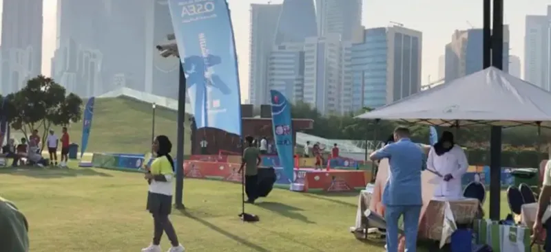 Outdoor fitness activity stations on a park lawn with the Doha skyline behind